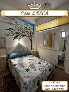 a bedroom with a bed with a tree painted on the wall at Casa Lasca in San Marzano di San Giuseppe
