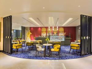 a restaurant with yellow chairs and tables and a bar at Grand Mercure Agra - An Accor Brand in Agra