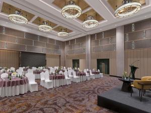 a banquet hall with tables and chairs and chandeliers at Grand Mercure Agra - An Accor Brand in Agra