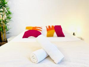 a white bed with two rolled towels on it at La Malterie - Machine à laver & WiFi in La Chapelle-Saint-Luc +3 photos