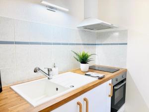 a white kitchen with a sink and a stove at La Malterie - Machine à laver & WiFi in La Chapelle-Saint-Luc