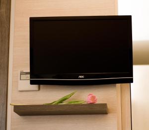 a tv on a wall with a flower on a shelf at Hotel Siena in Verona