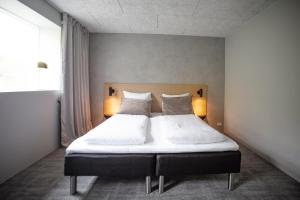 een slaapkamer met een bed met witte lakens en kussens bij Hotel Djurhuus in Tórshavn +49 foto's