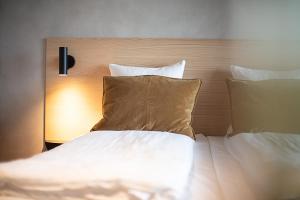 Una cama con sábanas blancas y almohadas en una habitación. en Hotel Djurhuus, en Tórshavn