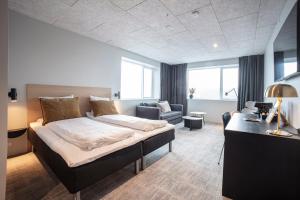 a bedroom with a bed and a couch and a chair at Hotel Djurhuus in Tórshavn