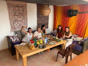 a group of women sitting around a wooden table at Surf & Skate in Taghazout