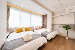 twee bedden in een kamer met een raam bij Terrace Tokyo Otsuka in Tokyo