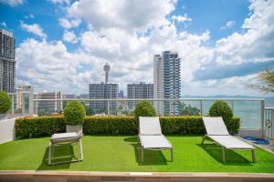 two chairs and a lawn on the roof of a building at 芭提雅瞰海无边泳景泳池健身房公寓 直达海滩椰子树旁 in Pattaya South