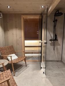 a glass shower door with a bench and a chair at House by the fjord in Vadsø