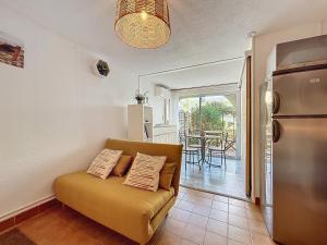 ein Wohnzimmer mit Couch und Küche in der Unterkunft Le Muge - Appartement Rez-de-chaussée - Piscine in Narbonne-Plage