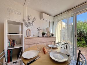 ein Esszimmer mit einem Tisch und einem großen Fenster in der Unterkunft Le Muge - Appartement Rez-de-chaussée - Piscine in Narbonne-Plage