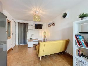 ein Wohnzimmer mit einem gelben Sofa und einem Fernseher in der Unterkunft Le Muge - Appartement Rez-de-chaussée - Piscine in Narbonne-Plage