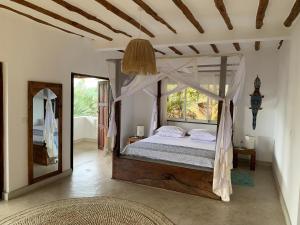 a bedroom with a canopy bed and a mirror at Sandy Feet Retreat in Malindi +5 photos