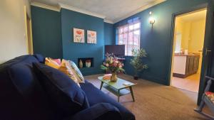 a blue living room with a couch and a table at Cosy and comfy 2 bedroom cottage with parking to the rear and a short drive from Cannock town centre in Hednesford