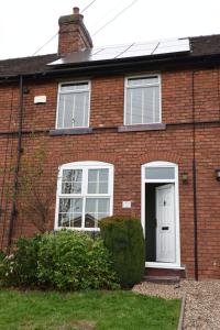 a red brick house with a white door at Cosy and comfy 2 bedroom cottage with parking to the rear and a short drive from Cannock town centre in Hednesford