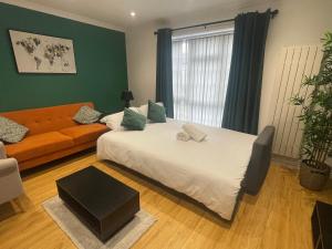 Un dormitorio con una cama grande y un sofá. en Rooms in stylish house, en Milton Keynes