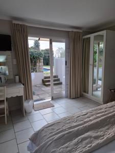 a bedroom with a bed and a desk and sliding glass doors at Avillahouse Guesthouse in Durban