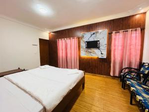 a bedroom with a bed and two chairs and a tv at Coolspot Cottage in Ooty