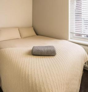 una cama con una almohada gris encima en Modern ROOM En-Suite Close to Hospital & Train, en Gillingham