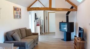 un salon avec un canapé et une télévision dans l'établissement Honey Suckle Hideaway, à Céaucé