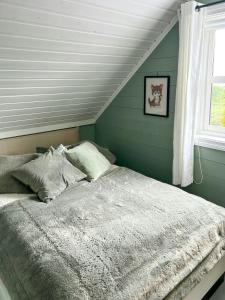 a bed in a bedroom with green walls and a window at Cabin With Sea Views In Mjømna 
