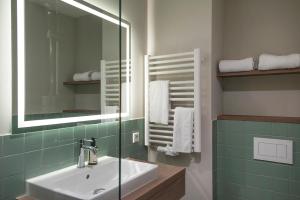 a bathroom with a sink and a mirror and towels at HUB Apartments St Georg in Hamburg