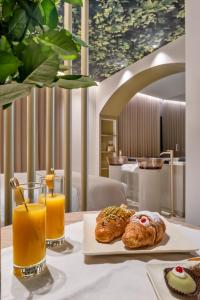 a table with two pastries and a glass of orange juice at Aquasuite - Luxury Experience & Spa in Palermo