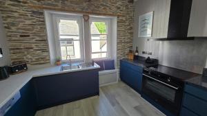a kitchen with blue cabinets and a sink and a window at Headmasters House in Port Isaac +7 photos