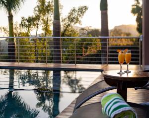 two glasses of wine on a table next to a swimming pool at Schimper View Boutique Guest House in Louis Trichardt