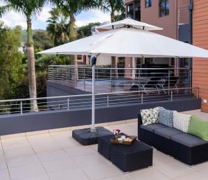 a patio with a couch and an umbrella at Schimper View Boutique Guest House in Louis Trichardt