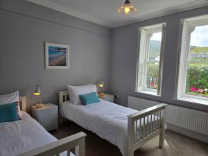 two beds in a room with two windows at Headmasters House in Port Isaac