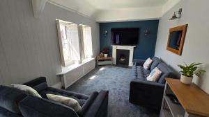 a living room with two blue couches and a fireplace at Headmasters House in Port Isaac