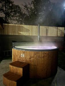 a hot tub with a bench in front of a fence at Pensiunea Sufletul Pădurii in Valea Lupului