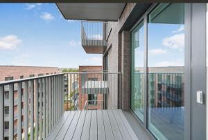 a balcony with glass doors and a chair on it at Casa Mono One Bedroom Flat in Southall
