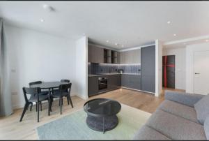 a living room with a couch and a table and a kitchen at Casa Mono One Bedroom Flat in Southall