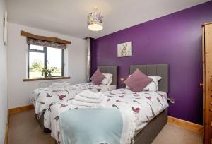 two beds in a bedroom with purple walls at Great Ash Barn in Copplestone