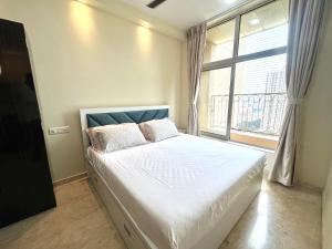 Un dormitorio con una cama con una ventana grande. en Picturesque LakeView Studio Apartment Hiranandani Estate Thane, en Thane