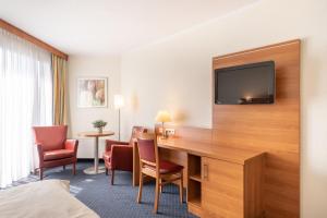 a hotel room with a desk with a television on a wall at Garner Hotel Bochum by IHG in Bochum