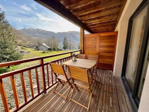 a wooden deck with a table and chairs on it at Appartement cosy au bords du lac de Loudenvielle in Génos