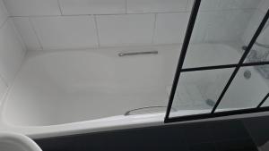 bañera blanca con ventana en el baño en Bitterne Homestay, en Southampton