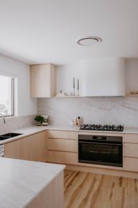 een keuken met houten kasten en een kookplaat met oven bij Phoenix Jervis Bay Family Coastal Escape in Vincentia