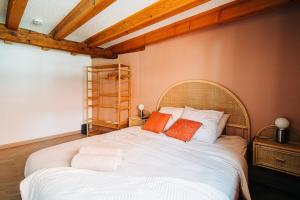 Un dormitorio con una gran cama blanca con almohadas naranjas. en Chai d'oeuvre, en Dambach-la-Ville