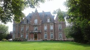un grand bâtiment en briques avec une pelouse verte devant lui dans l'établissement Château des marronniers, à Baizieux