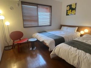 a bedroom with two beds and a chair and a window at Yotsuya Lantern - Private 3 stories house for family in Tokyo