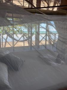 a white bed in a room with a window at Popochos Beach Eco Lodge in Nuquí +68 photos