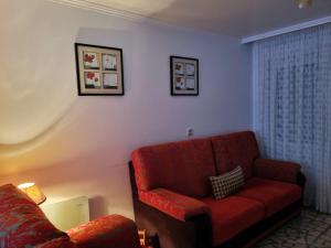 sala de estar con silla roja y sofá en O Curro de Arou, en Arou