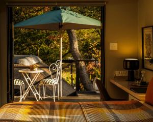 a table and chairs with an umbrella on a porch at Moontide Riverside Lodge in Wilderness