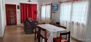a living room with a table and chairs and a red curtain at Casa temporada 2026 in Miramar