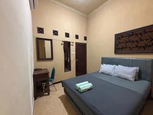a bedroom with a blue bed with a desk and a computer at Good Feeling Ijen Banyuwangi in Banyuwangi