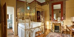 a bedroom with a metal canopy bed and a fireplace at Hotel-Musée Villa Bagatelle in Irigny